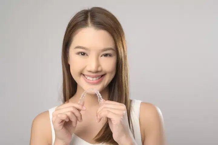 A female teen holding her Invisalign aligners